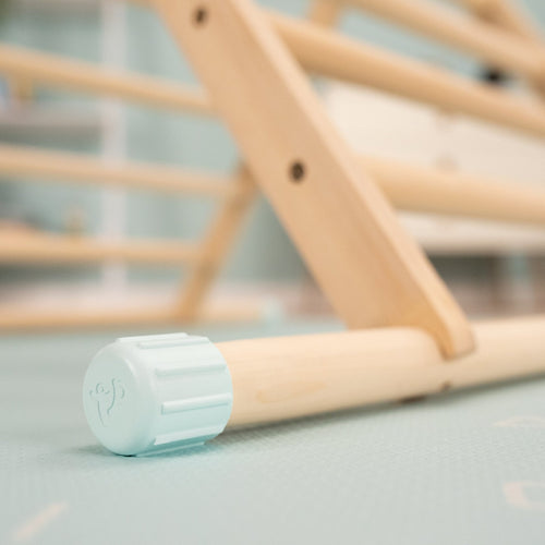 Close-up of the TP Toys TP Active-Tots Pikler Style Climbing Triangle, Cube & Three Slides—FSC® certified—with a light blue rubber end cap, shown resting on a soft textured floor.