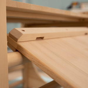 Close-up of the TP Toys TP Active-Tots Pikler Style Wooden Climbing Bridge and Slide, made from FSC® certified light wood, highlights its smooth unfinished surfaces and simple adjustable mechanism.
