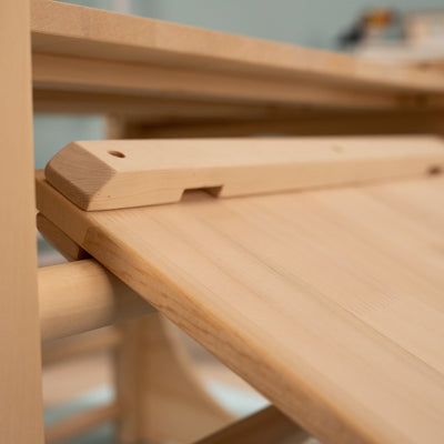 Close-up of the TP Toys TP Active-Tots Pikler Style Wooden Climbing Bridge and Slide, made from FSC® certified light wood, highlights its smooth unfinished surfaces and simple adjustable mechanism.