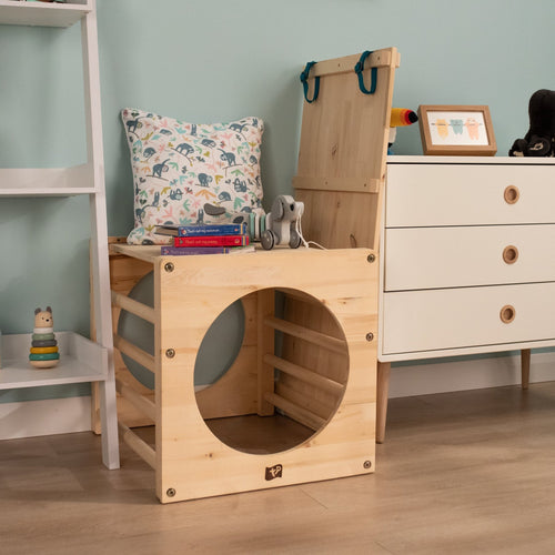 The TP Active-Tots Pikler Style Wooden Climbing Bridge and Slide by TP Toys, FSC® certified, is featured in a childrens room alongside books, toys, and playful decor for creative indoor play.