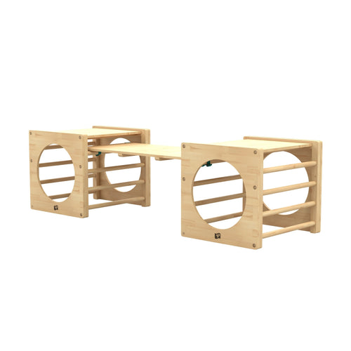 The TP Toys Active-Tots Pikler Style Two Climbing Cubes & Bridge, made from FSC® certified wood, features cube frames with circular openings and a plank bridge—perfect as a sturdy Montessori toy for active indoor climbing and imaginative play.