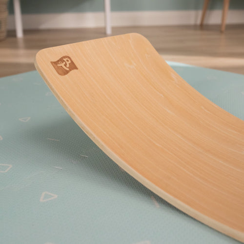 The TP Toys TP Active-Tots Pikler Style Wooden Balance Board, made from FSC® certified wood, sits on the table and offers kids a fun way to boost gross motor skills through play.