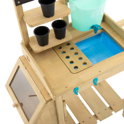 The TP Wooden Explore Potting Bench by TP Toys features shelves with black pots, a green bucket, a blue sink, and a slotted work surface. A glass-doored cabinet sits on the left—ideal as a children’s gardening station. FSC® certified wood.