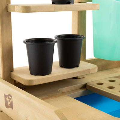 The TP Toys Wooden Deluxe Potting Bench (FSC® certified) features black plastic pots, a blue plastic bin, and a perforated wooden panel—ideal for organizing gardening play accessories.