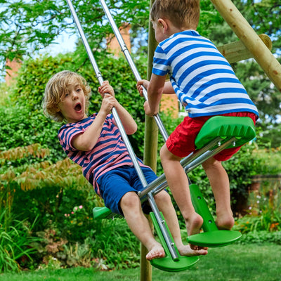 Two young boys in striped shirts and shorts play on a TP Toys Kingswood Double Squarewood Swing Set with Glider – FSC® certified, in a garden. One boy looks surprised as both hold onto the metal bars.