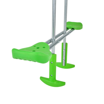 A close-up of green and metal stilts for walking, placed beside the TP Toys TP Sherwood Triple Wooden Swing Set (PEFC certified) in a garden setting.