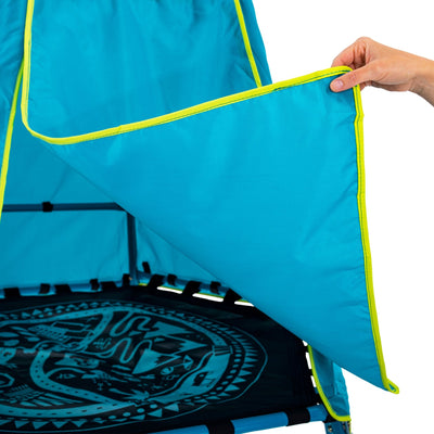 A hand lifts the corner of a blue fabric cover with yellow trim, revealing the TP Explorer Metal Climbing Frame Set & Ripple Slide by TP Toys—perfect for pairing with an adventure playmat.